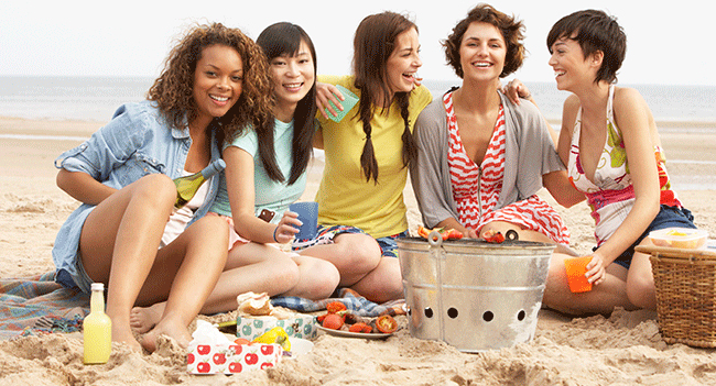 A group of female friends sitting on the beach discussing what their Marietta, Ohio dentist told them about wisdom teeth.